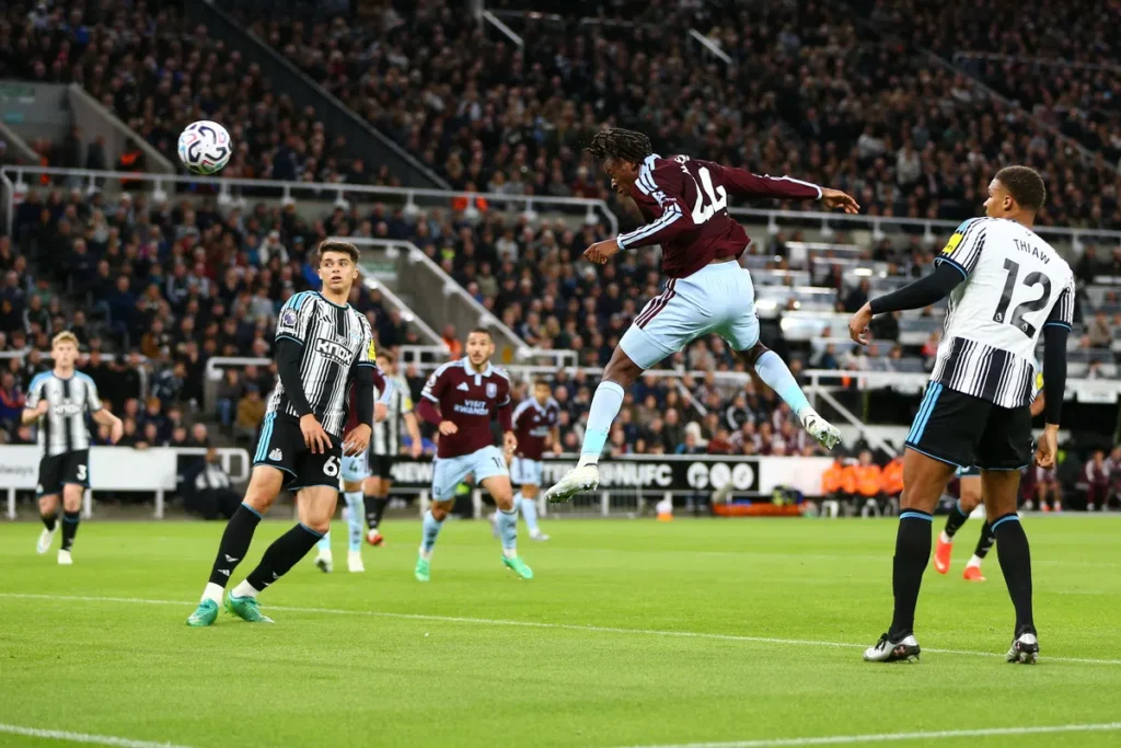 Spelers van Aston Villa en Newcastle United springen voor de bal tijdens een Premier League-wedstrijd.