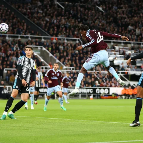 Spelers van Aston Villa en Newcastle United springen voor de bal tijdens een Premier League-wedstrijd.