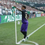 Lamine Yamal staat bij de hoekvlag in een stadion, met een groen-witte vlag in zijn hand.