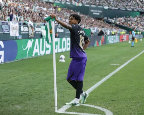 Lamine Yamal staat bij de hoekvlag in een stadion, met een groen-witte vlag in zijn hand.