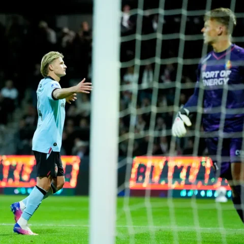 Sem Steijn in lichtblauw shirt juicht naast het doel tijdens een voetbalwedstrijd, met de keeper in paars op de achtergrond.
