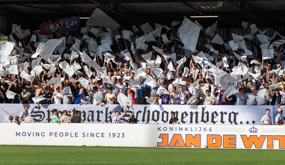 Supporters in een stadion zwaaien met witte vlaggen tijdens een voetbalwedstrijd.