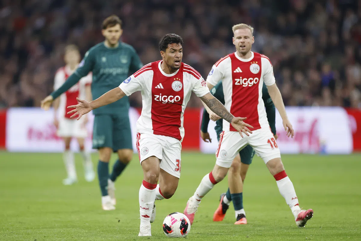 Ajax-spelers in actie tijdens een voetbalwedstrijd, met een speler in het rood-wit op de voorgrond bij de bal.