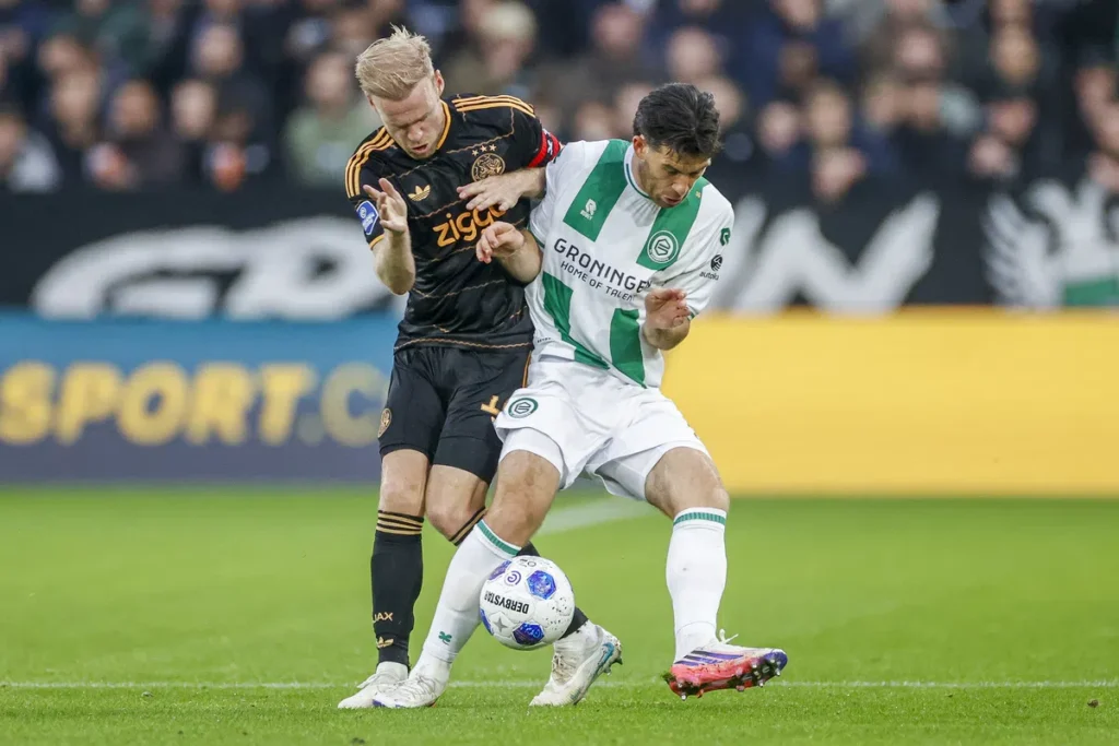 Davy Klaassen in Ajax shirt duels for the ball with a Groningen player during a football match.