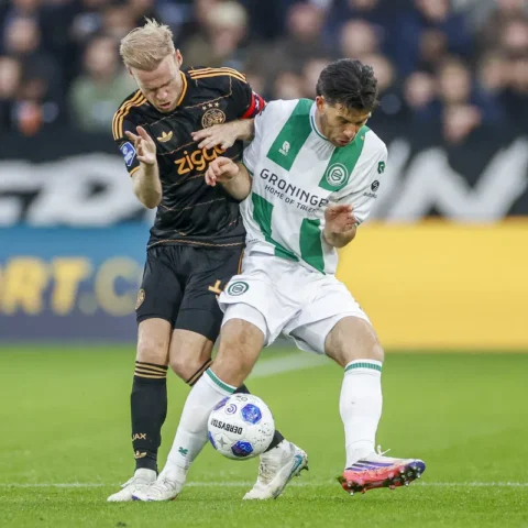 Davy Klaassen in Ajax shirt duels for the ball with a Groningen player during a football match.