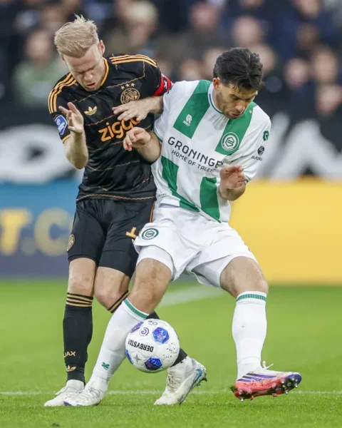 Davy Klaassen in Ajax shirt duels for the ball with a Groningen player during a football match.