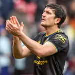 Lisandro Martínez applauds on the pitch in a Manchester United away kit.