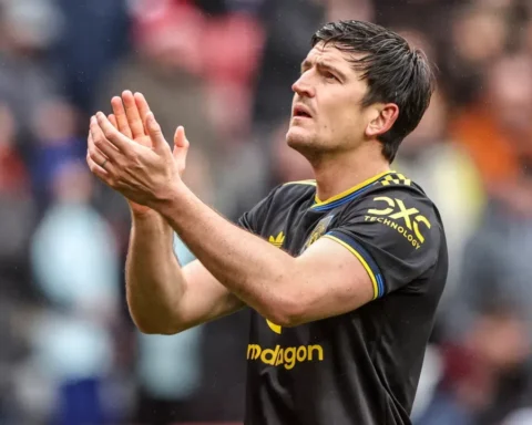 Lisandro Martínez applauds on the pitch in a Manchester United away kit.