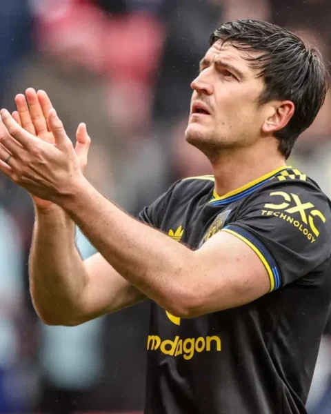 Lisandro Martínez applauds on the pitch in a Manchester United away kit.