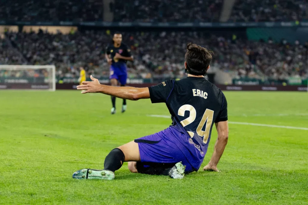 FC Barcelona speler Eric zit op het veld tijdens een wedstrijd in een stadion.