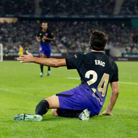FC Barcelona speler Eric zit op het veld tijdens een wedstrijd in een stadion.