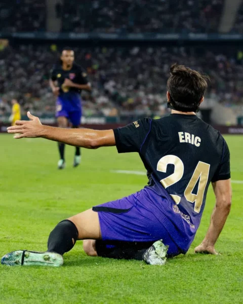FC Barcelona speler Eric zit op het veld tijdens een wedstrijd in een stadion.