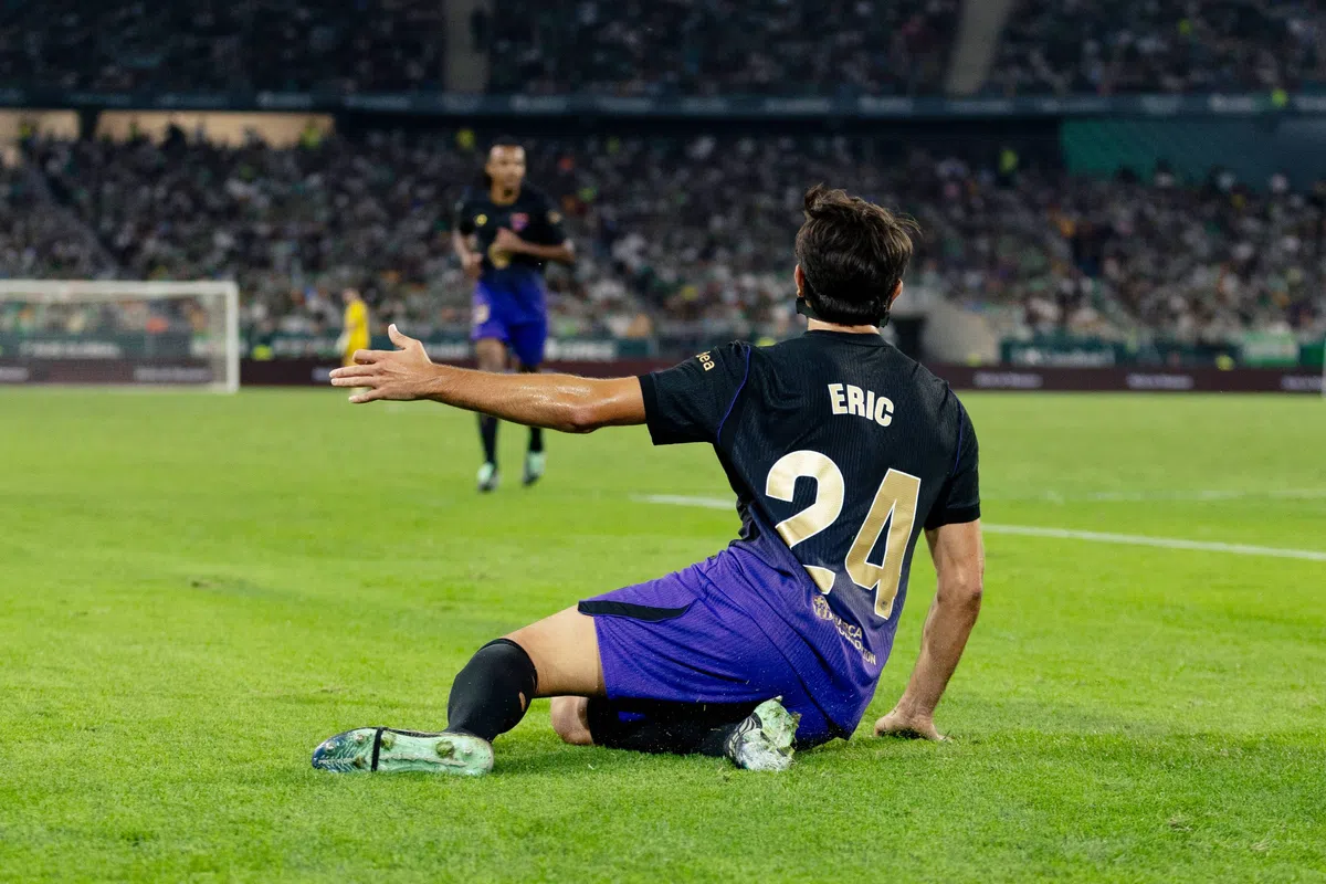 FC Barcelona speler Eric zit op het veld tijdens een wedstrijd in een stadion.