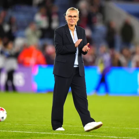 Sarina Wiegman applauds on the touchline during a football match.