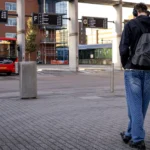Een reiziger wacht bij een bushalte terwijl een bus op het station staat.