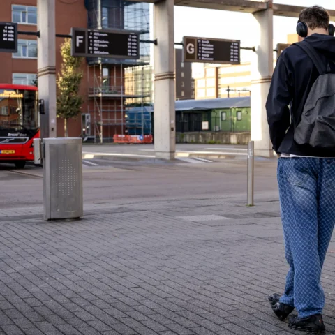 Een reiziger wacht bij een bushalte terwijl een bus op het station staat.