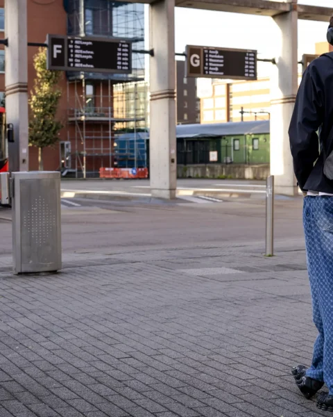 Een reiziger wacht bij een bushalte terwijl een bus op het station staat.