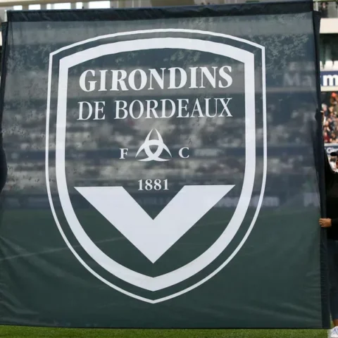 Twee vrouwen houden een groot Girondins de Bordeaux-doek vast in een stadion.