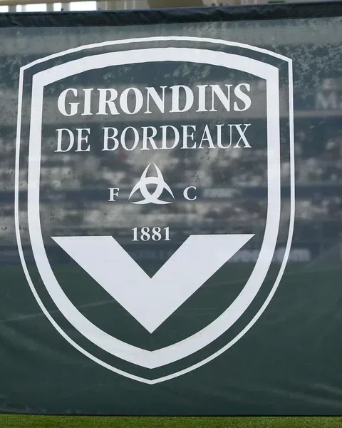 Twee vrouwen houden een groot Girondins de Bordeaux-doek vast in een stadion.