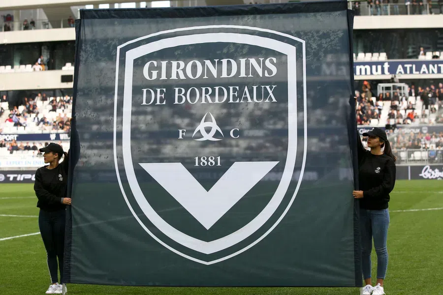 Twee vrouwen houden een groot Girondins de Bordeaux-doek vast in een stadion.