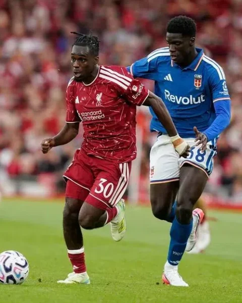 Jeremie Frimpong in een voetbalwedstrijd tussen Liverpool en een ploeg in blauw shirt.