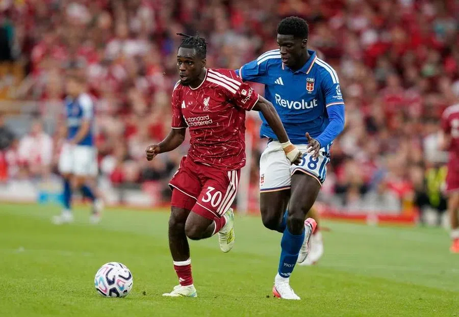 Jeremie Frimpong in een voetbalwedstrijd tussen Liverpool en een ploeg in blauw shirt.