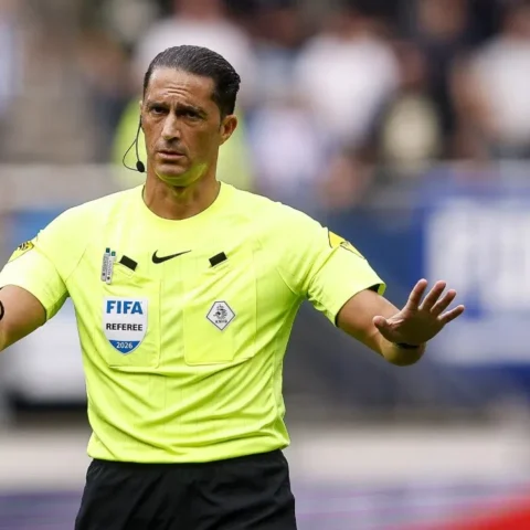 Scheidsrechter Serdar Gözübüyük gebaart op het veld in een felle gele FIFA-referee outfit.