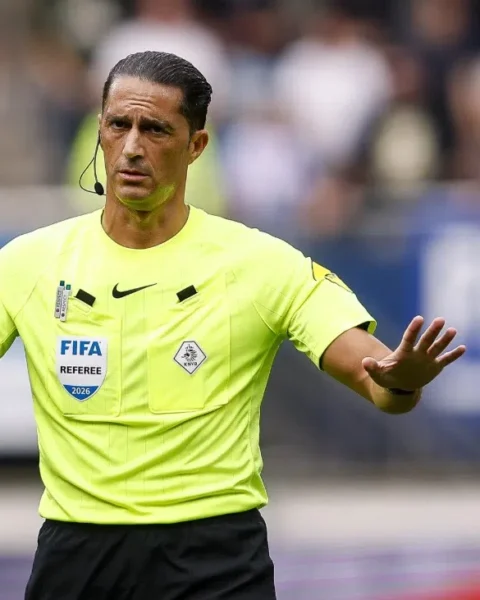 Scheidsrechter Serdar Gözübüyük gebaart op het veld in een felle gele FIFA-referee outfit.