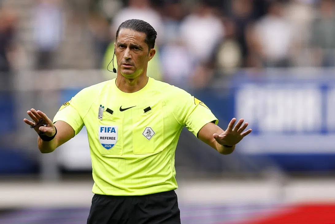 Scheidsrechter Serdar Gözübüyük gebaart op het veld in een felle gele FIFA-referee outfit.