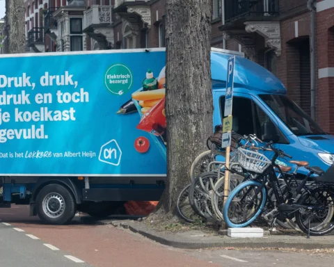 Albert Heijn-bezorgwagen geparkeerd in een straat met fietsen op de stoep.