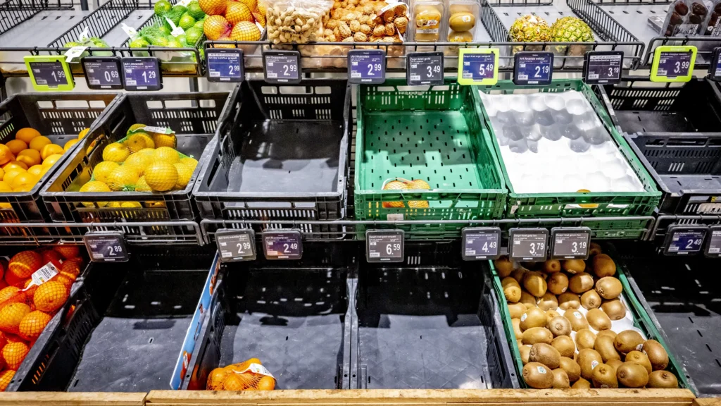 Lege en deels gevulde groenterekken met citrus en kiwi's in een Albert Heijn-supermarkt.