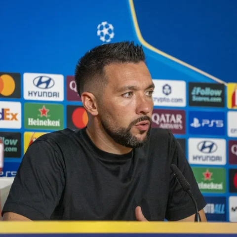 Francesco Farioli spreekt op een Champions League-persconferentie voor een sponsorachtergrond.