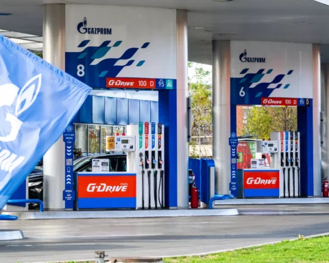 Gazprom-branded gas station pumps under a canopy, with a blue Gazprom flag in the foreground.