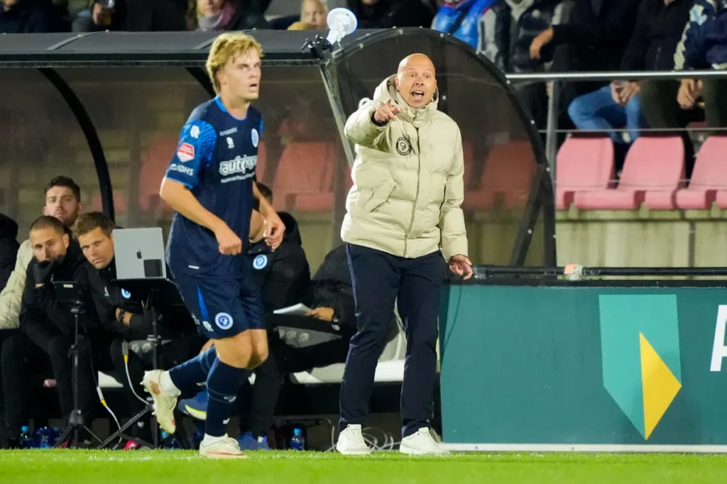 Trainer van De Graafschap geeft aanwijzingen langs de zijlijn tijdens een wedstrijd.