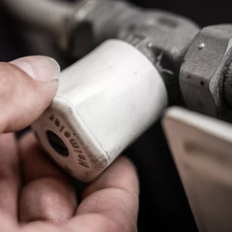 Close-up van een hand die een mechanisch onderdeel vasthoudt.