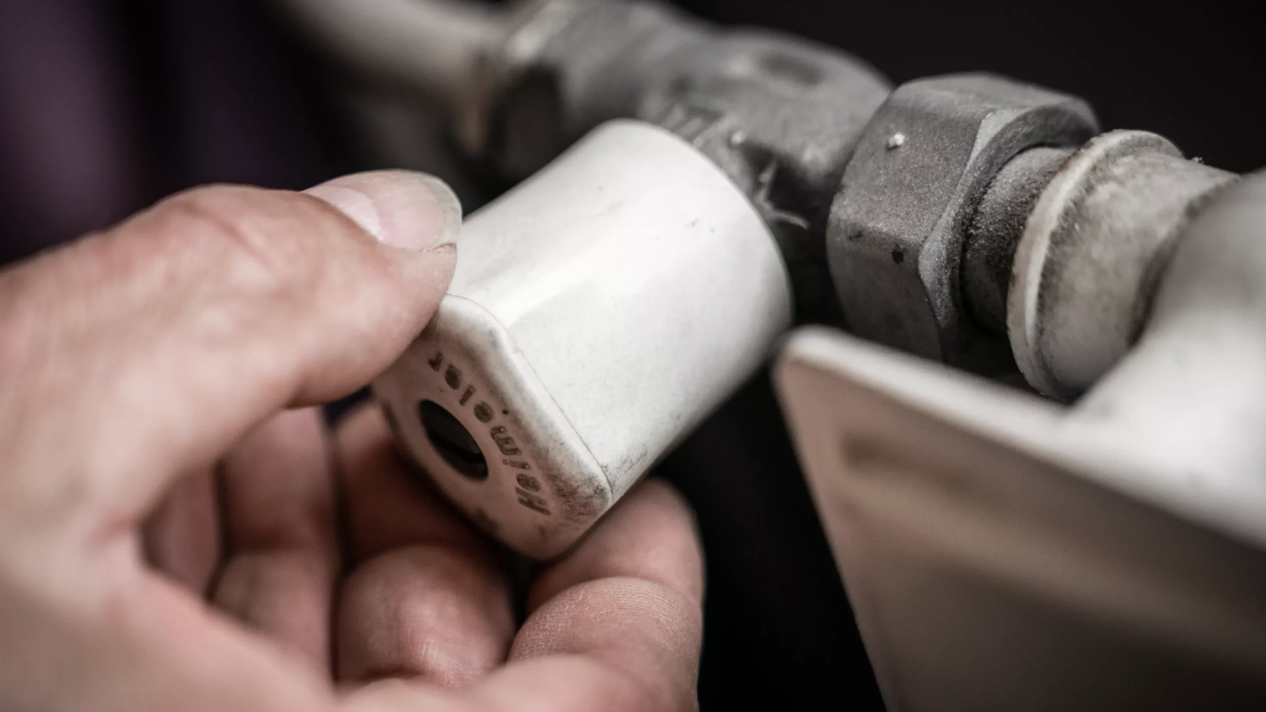Close-up van een hand die een mechanisch onderdeel vasthoudt.