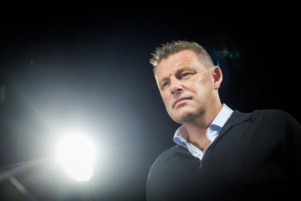 John Stegeman staat in een donkere setting met fel tegenlicht.