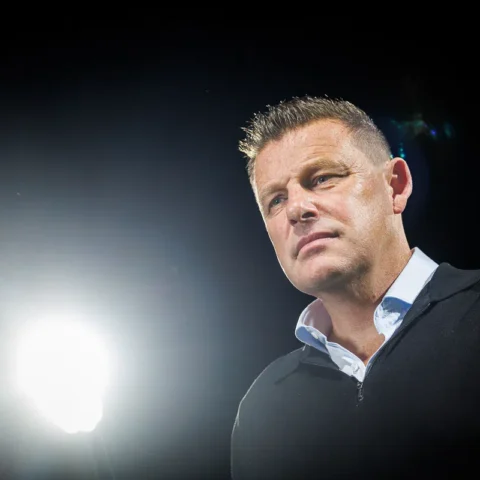 John Stegeman staat in een donkere setting met fel tegenlicht.