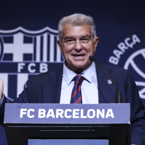 Joan Laporta spreekt bij een FC Barcelona-podium voor een blauw clubachtergrondscherm.