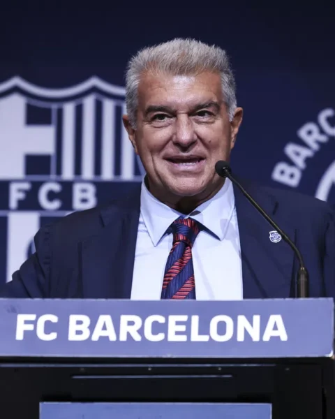 Joan Laporta spreekt bij een FC Barcelona-podium voor een blauw clubachtergrondscherm.