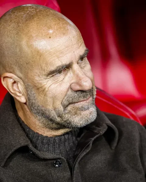 Peter Bosz zit op de bank in een rood stadionstoeltje.