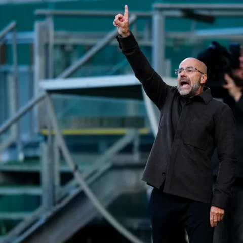 Trainer geeft instructies langs de zijlijn in een stadion.
