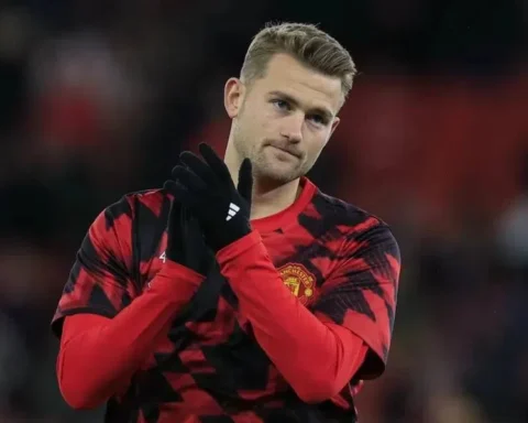 Matthijs de Ligt in een rood-zwarte Manchester United warming-upshirt, klappend op het veld.
