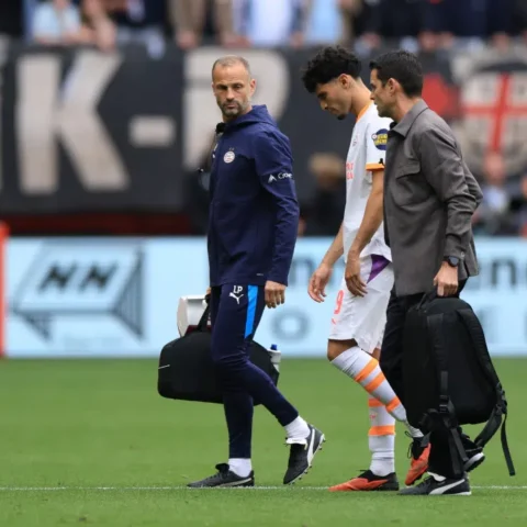 PSV-trainer Peter Bosz loopt langs de zijlijn naast een speler en een staflid op het veld.