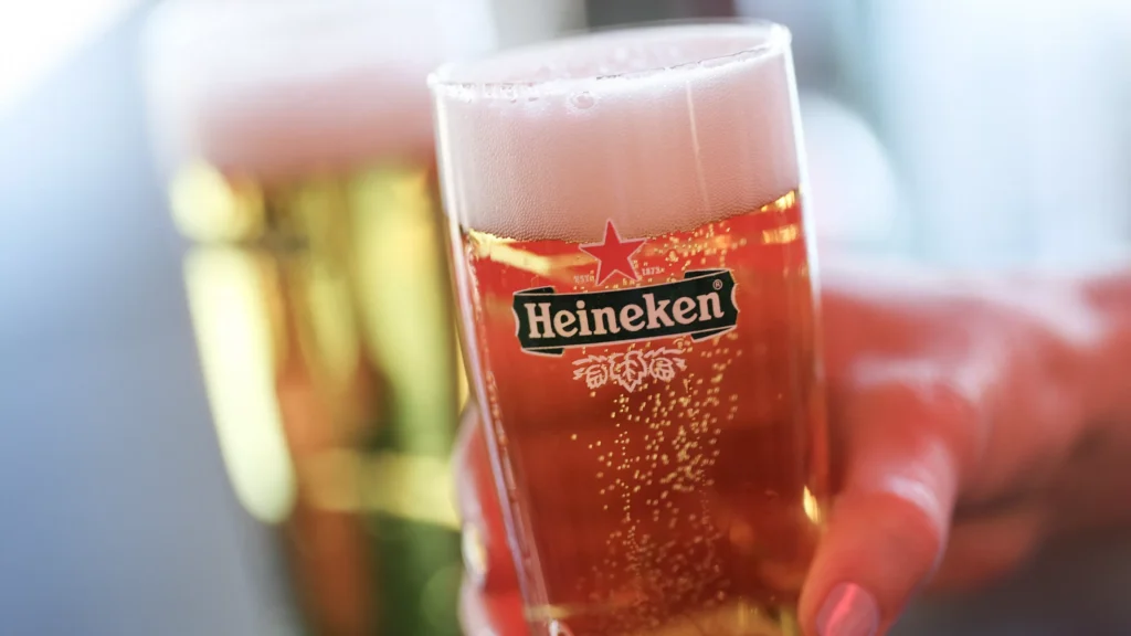Glas met Heineken-bier met schuimkraag op de voorgrond.