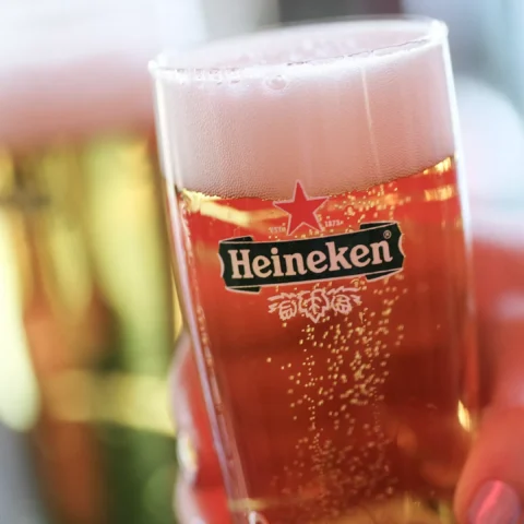 Glas met Heineken-bier met schuimkraag op de voorgrond.