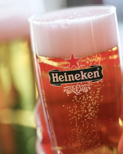 Glas met Heineken-bier met schuimkraag op de voorgrond.