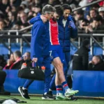 Khvicha Kvaratskhelia wordt ondersteund door stafleden langs de zijlijn tijdens een PSG-wedstrijd.