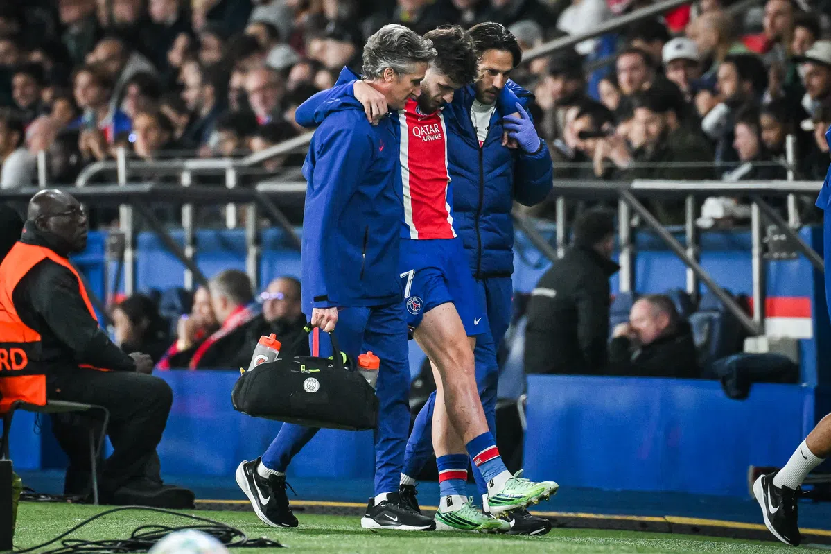 Khvicha Kvaratskhelia wordt ondersteund door stafleden langs de zijlijn tijdens een PSG-wedstrijd.