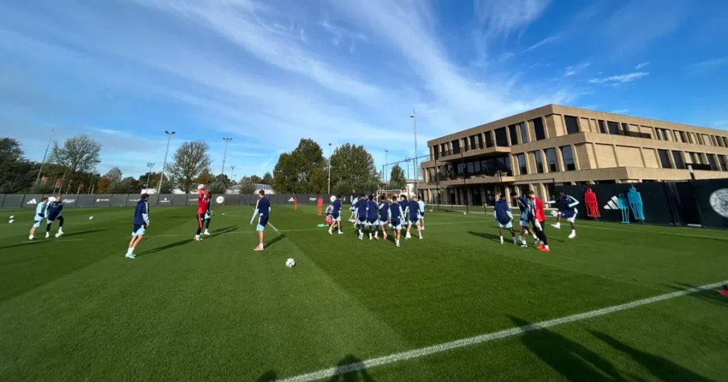 Ajax-spelers trainen op het veld naast het clubgebouw.